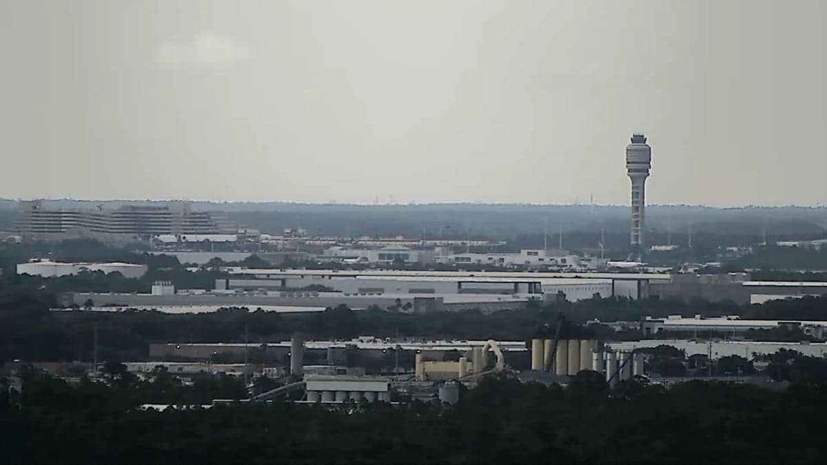 Fachada do Aeroporto Internacional de Orlando com palmeiras e céu azul ao fundo