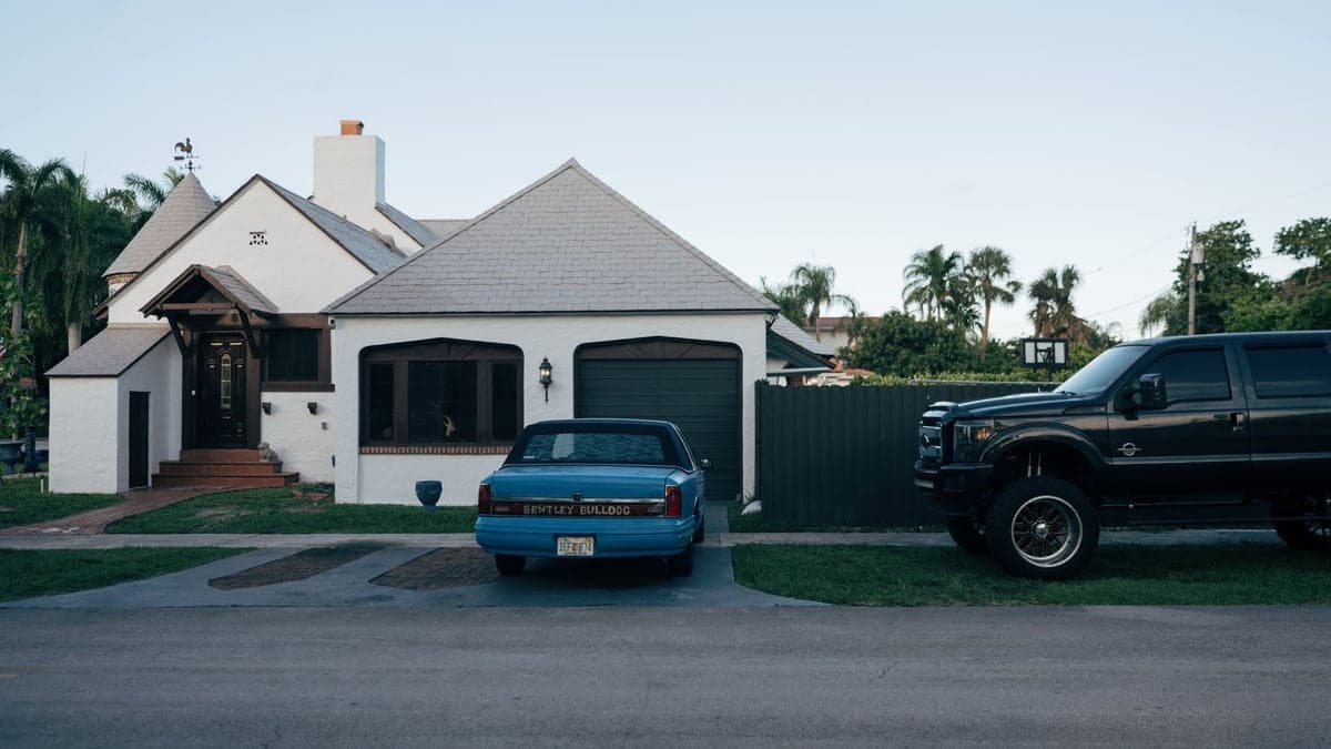 Casa residencial em bairro dos Estados Unidos com dois carros estacionados na garagem e na entrada
