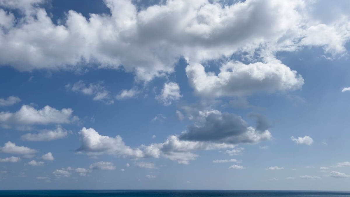 Mar aberto sob céu azul com nuvens brancas esparsas
