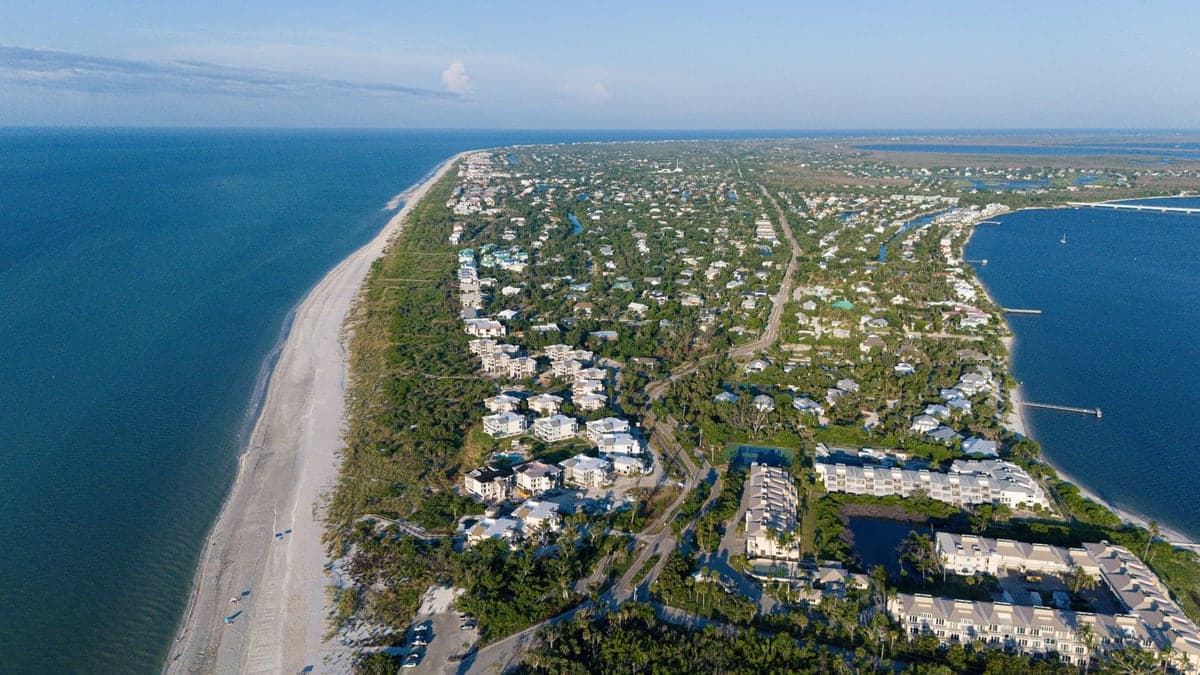 vista aérea de uma península com praias, casas e vegetação ao longo da costa