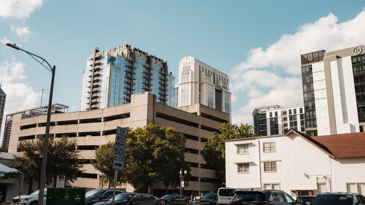 Prédios altos no centro de Orlando com um estacionamento grande em primeiro plano e vários carros estacionados