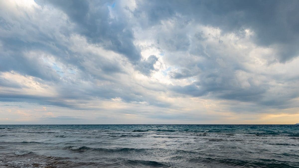 praia com mar agitado e céu nublado com nuvens pesadas, indicando possível tempestade