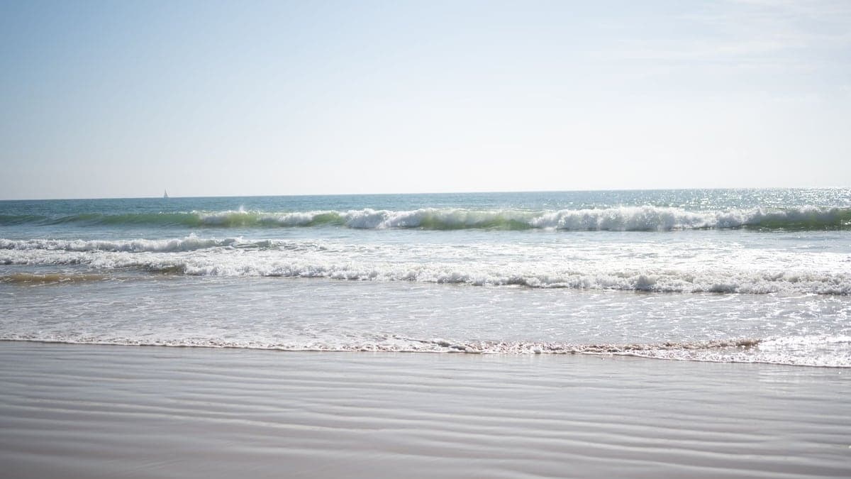 Ondas fortes quebrando perto da faixa de areia da praia sob céu claro