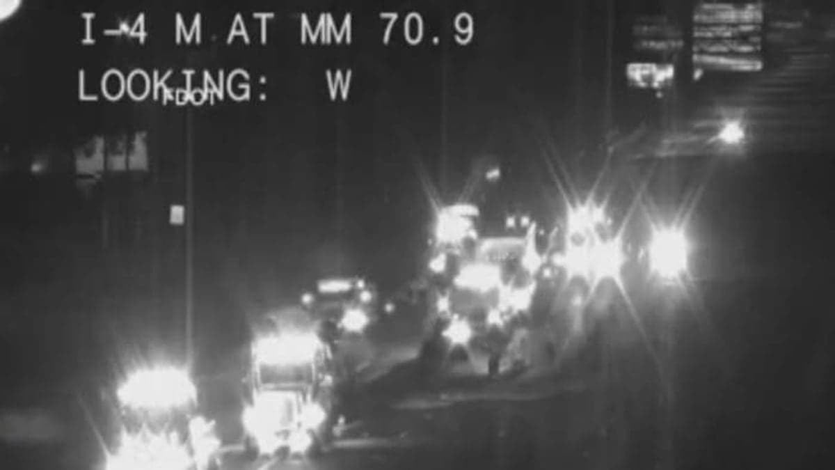 Imagem da Interstate 4 em Orlando, mostrando a rodovia com placas de sinalização e palmeiras ao redor sob céu azul