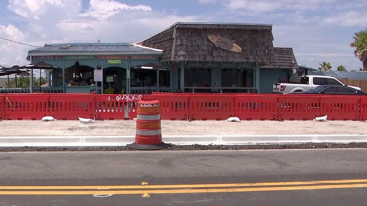 Trecho da estrada com obras, mostrando faixa de estacionamento reduzida, guias e calçada compartilhada em Ormond-by-the-Sea
