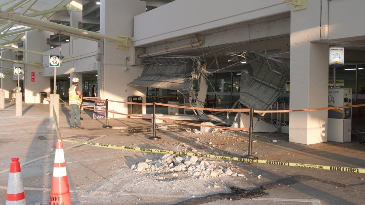 Área externa próxima ao Terminal A do Aeroporto Internacional de Orlando, com vagas de estacionamento para ônibus e área de veículos comerciais visíveis sob luz do dia.