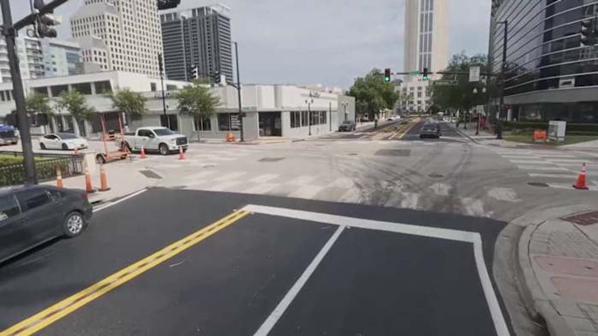 Imagem da Magnolia Avenue em Downtown Orlando com ruas de dois sentidos, carros estacionados e prédios baixos ao fundo em um dia ensolarado