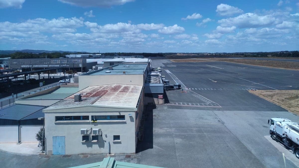Vista aérea do aeroporto de Kissimmee com pista, taxiways e terminal ao lado sob céu azul com poucas nuvens