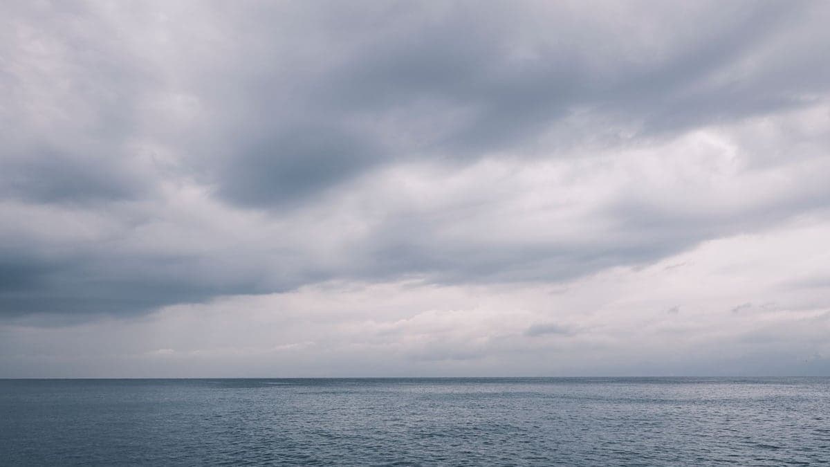 vista do oceano sob céu carregado de nuvens cinzentas, com horizonte onde o mar encontra o céu nublado