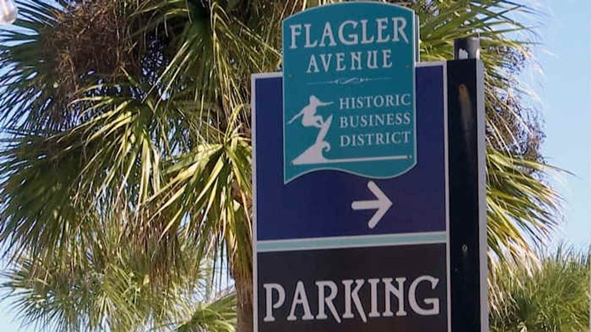 Rua com estacionamentos e palmeiras em área próxima à praia em New Smyrna Beach, na Flórida.