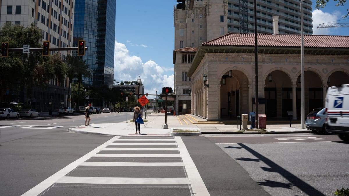 Cruzamento urbano de Orlando com semáforos e pedestres atravessando a faixa de pedestres em dia ensolarado