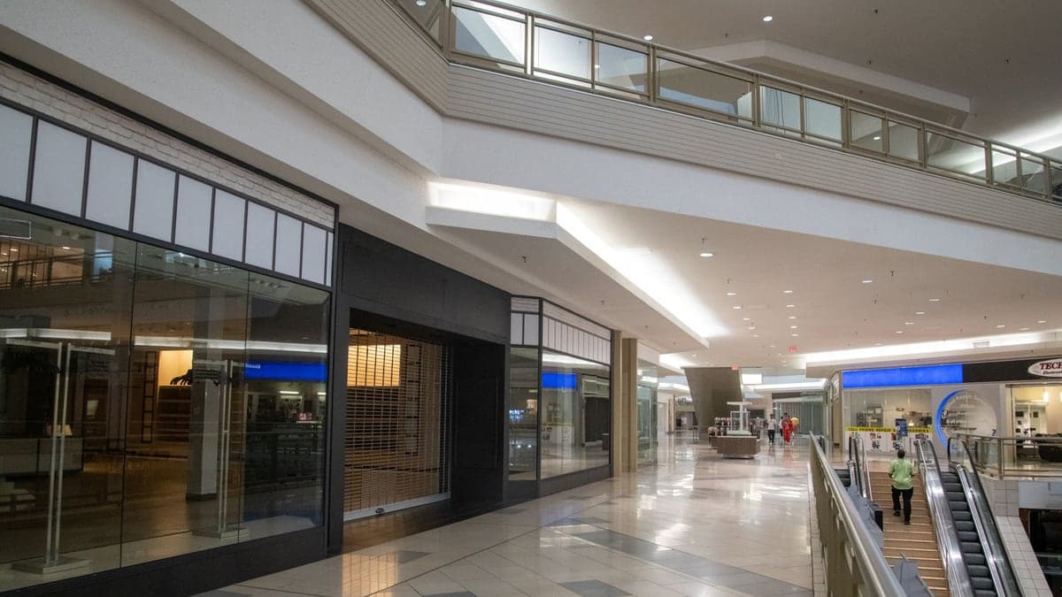 Corredor interno de shopping center com várias lojas fechadas e sem clientes