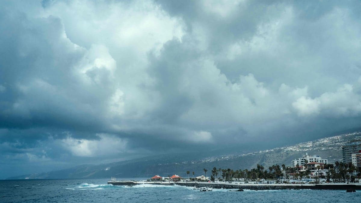 Vista do litoral com mar agitado e céu nublado carregado de nuvens escuras, indicando tempestade próxima