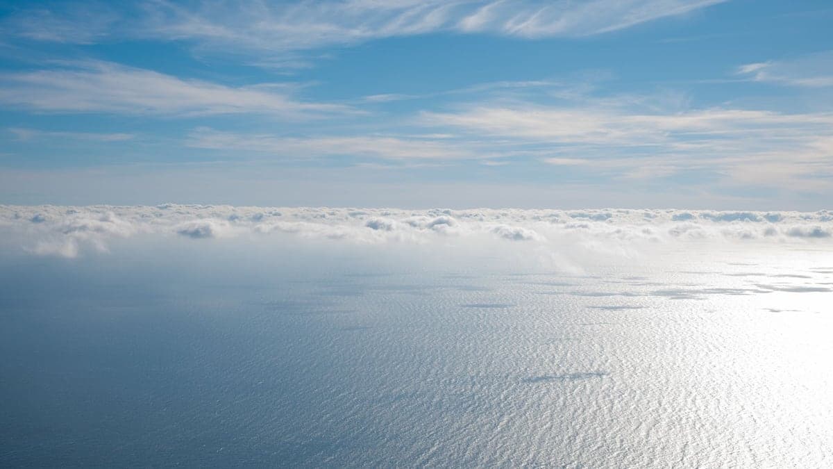 Vista aérea do oceano Atlântico com nuvens dispersas no céu azul claro