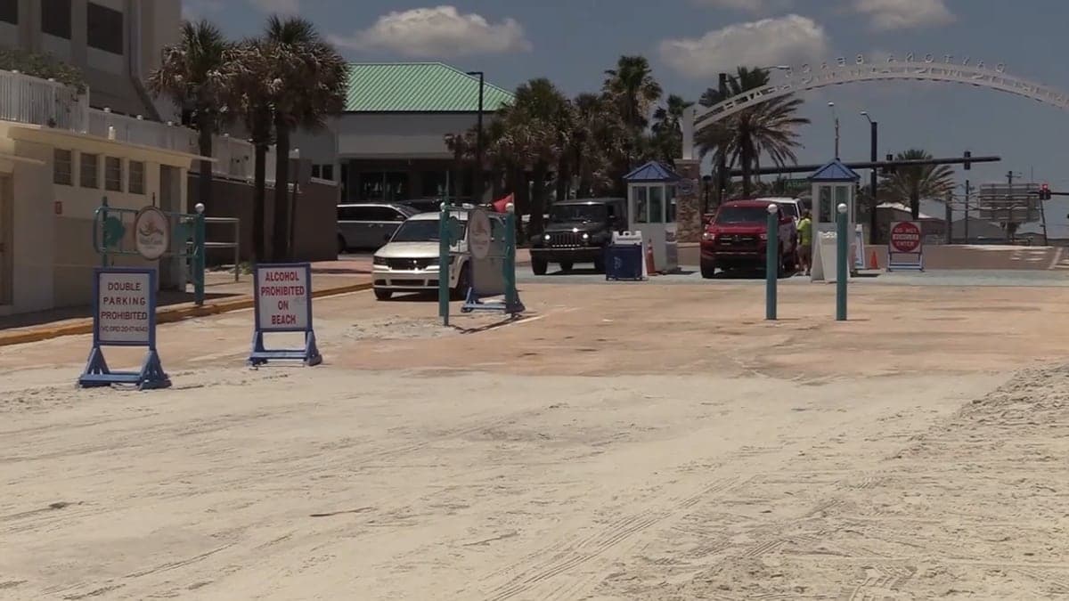 Vagas de estacionamento próximas a uma praia da Flórida com céu azul e palmeiras ao fundo, sem carros estacionados
